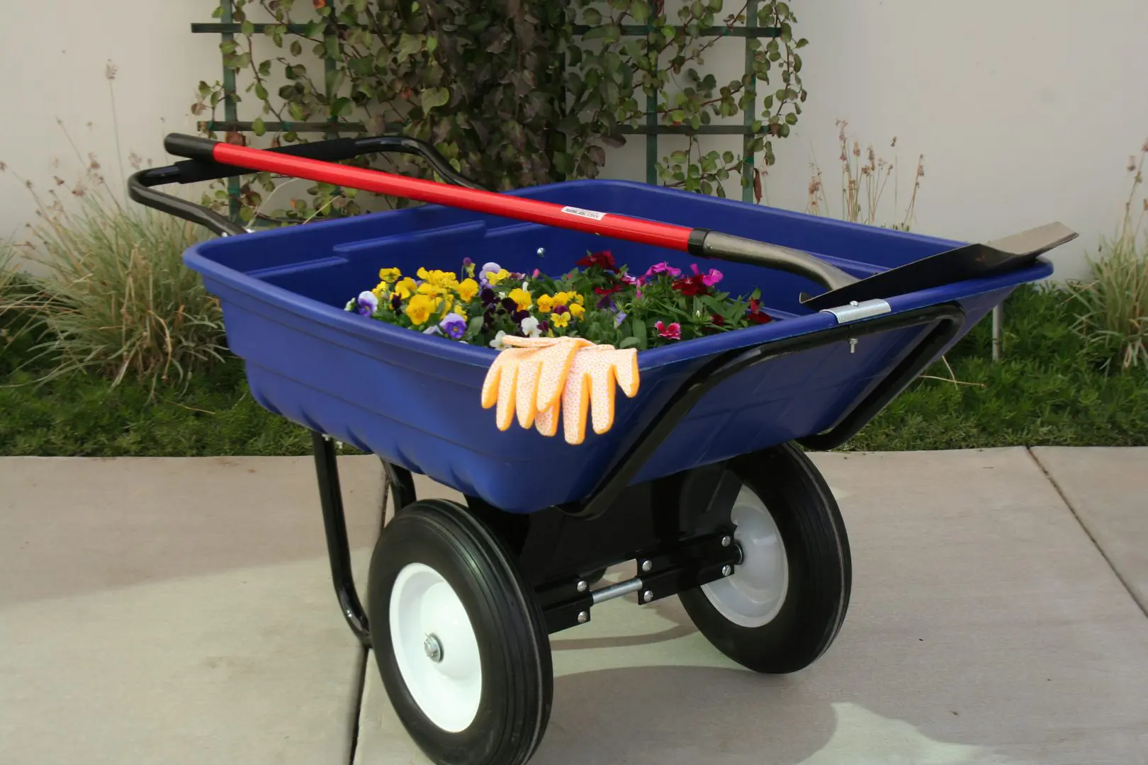 A blue wagon with flowers in it and a hand on the handle.